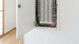 住宅の分電盤と契約内容を確認する様子